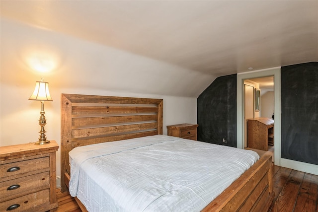 bedroom with lofted ceiling and dark wood finished floors