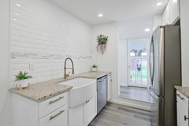 286 9th St, Verplanck, NY 10596 - kitchen featuring appliances with stainless steel finishes, a sink, light wood-style floors, tasteful backsplash, and white cabinets