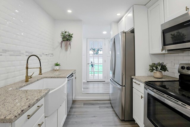 286 9th St, Verplanck, NY 10596 - kitchen featuring appliances with stainless steel finishes, a sink, backsplash, light wood-style floors, and white cabinetry