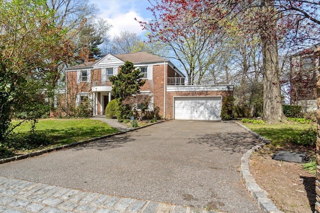 view of front facade with brick siding, a front lawn, aphalt driveway, and a balcony