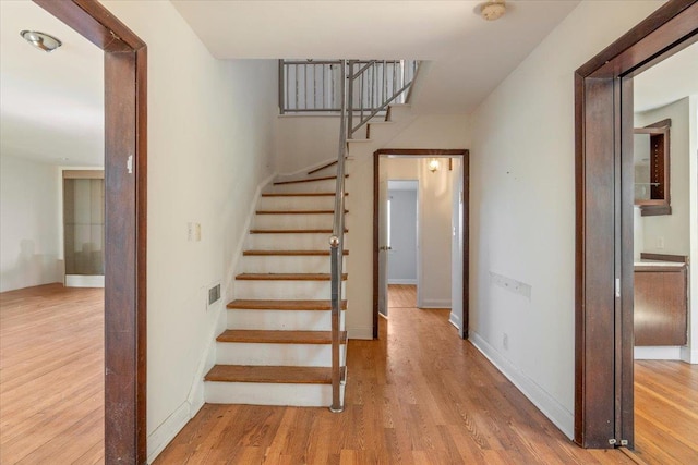 stairs with visible vents, baseboards, and wood finished floors