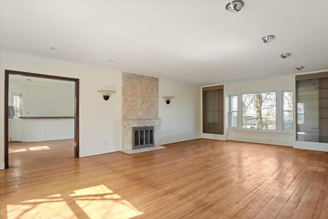 unfurnished living room with light wood-style flooring and a tile fireplace