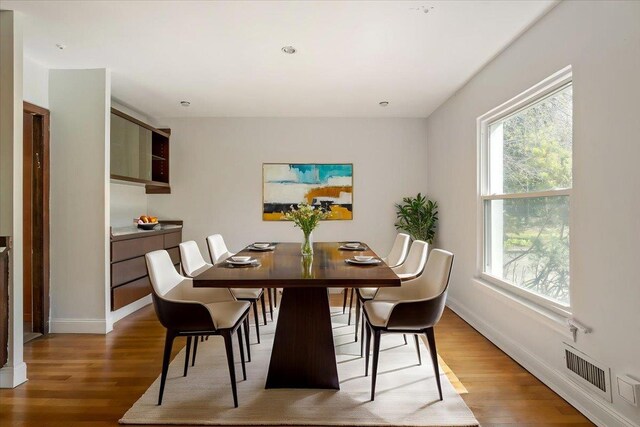 dining area with visible vents, light wood finished floors, and a healthy amount of sunlight