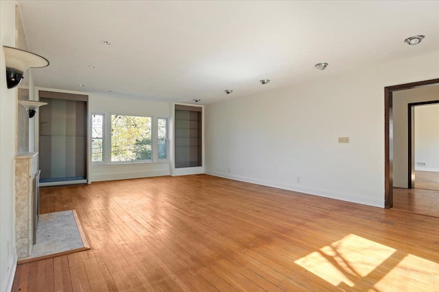 unfurnished living room featuring baseboards and light wood-type flooring
