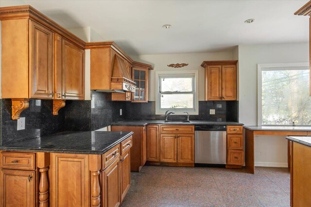 kitchen featuring a sink, brown cabinetry, granite finish floor, glass insert cabinets, and dishwasher