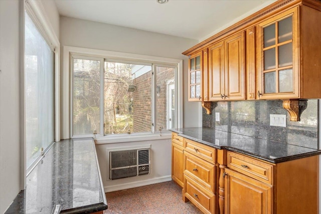 kitchen with brown cabinetry, baseboards, glass insert cabinets, and tasteful backsplash