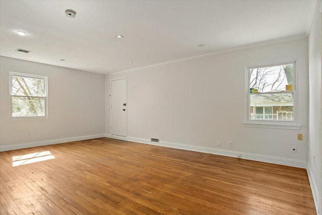 unfurnished room with a wealth of natural light, visible vents, light wood finished floors, and baseboards
