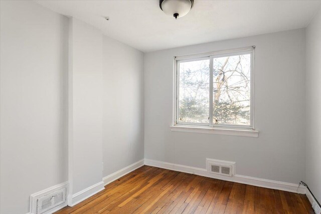 empty room with wood-type flooring, visible vents, baseboards, and baseboard heating
