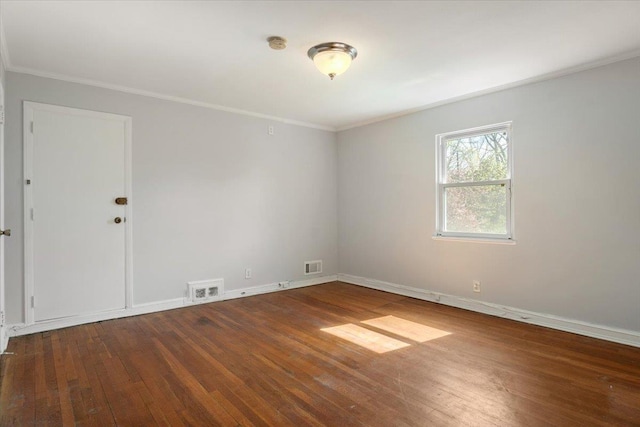 spare room with hardwood / wood-style floors, visible vents, and ornamental molding