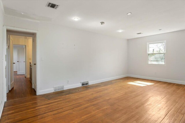 spare room featuring wood-type flooring, baseboards, and visible vents