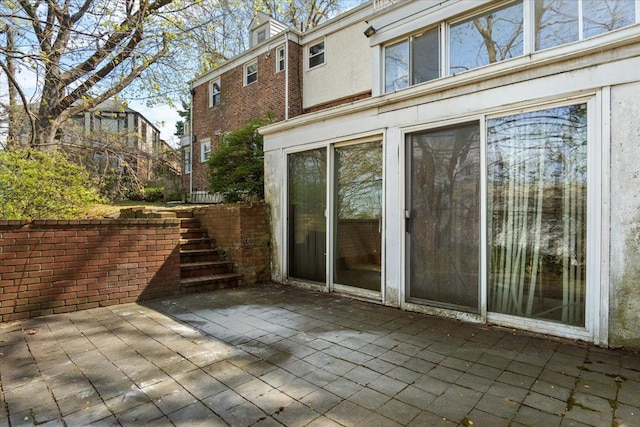 rear view of property featuring a patio area, stairs, and stucco siding