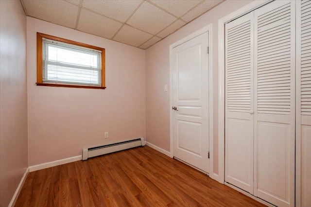 92 Nebraska St, Long Beach, NY 11561 - unfurnished bedroom with a baseboard radiator, baseboards, a drop ceiling, and light wood-style flooring