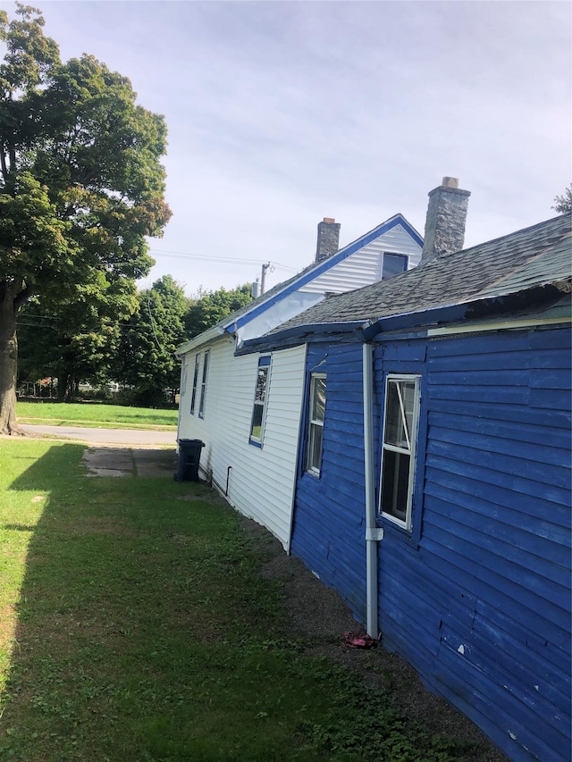 view of side of property featuring a chimney and a yard