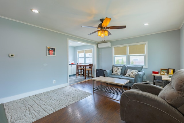 living room with wood finished floors, an AC wall unit, a ceiling fan, crown molding, and baseboards