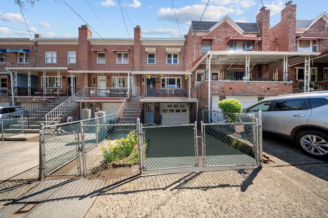 multi unit property featuring a gate, an attached garage, brick siding, and stairway