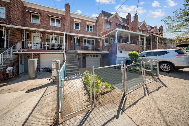 townhome / multi-family property with a gate, brick siding, stairway, and driveway