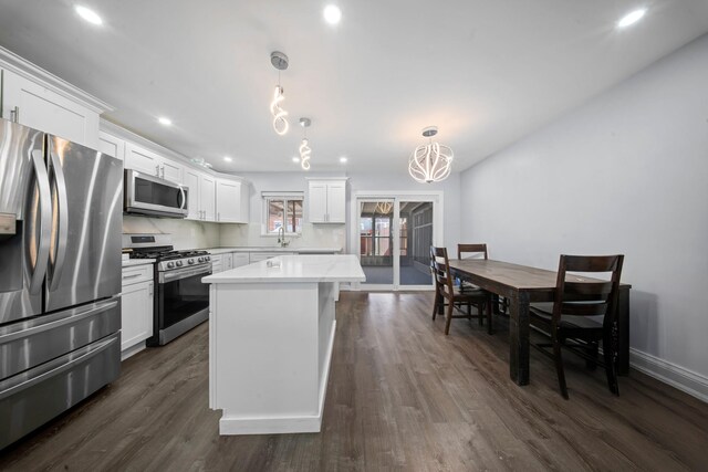 kitchen with white cabinets, dark wood-style floors, light countertops, a kitchen island, and appliances with stainless steel finishes
