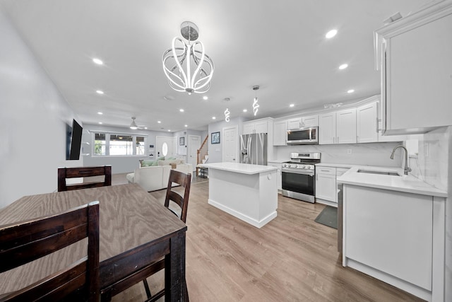 kitchen featuring a center island, a sink, stainless steel appliances, white cabinets, and recessed lighting