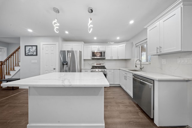 kitchen featuring white cabinets, stainless steel appliances, a sink, a kitchen island, and dark wood-style flooring