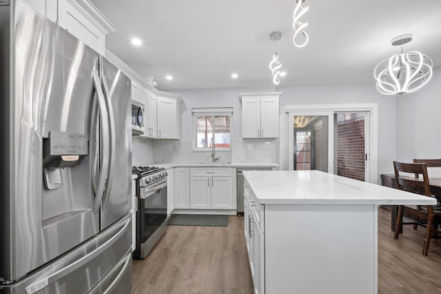 kitchen featuring white cabinets, wood finished floors, stainless steel appliances, and a sink