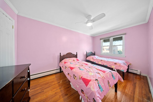 bedroom featuring wood finished floors, crown molding, and baseboard heating