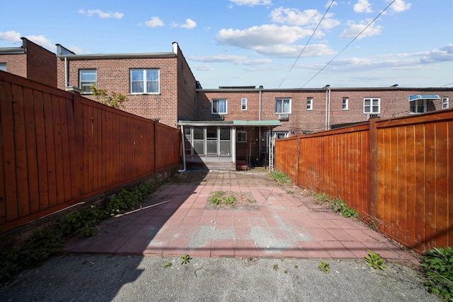 rear view of property featuring a fenced backyard, brick siding, and a patio