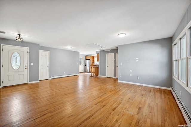 unfurnished living room with light wood-style floors, a baseboard heating unit, and baseboards