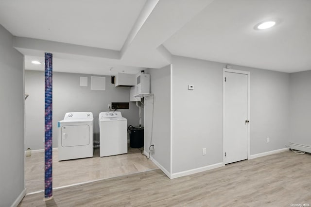 clothes washing area with baseboards, wood finished floors, and separate washer and dryer