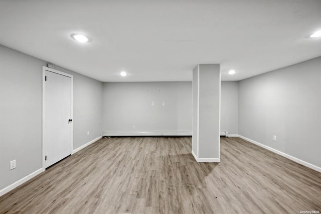 finished below grade area with recessed lighting, baseboard heating, wood finished floors, and baseboards