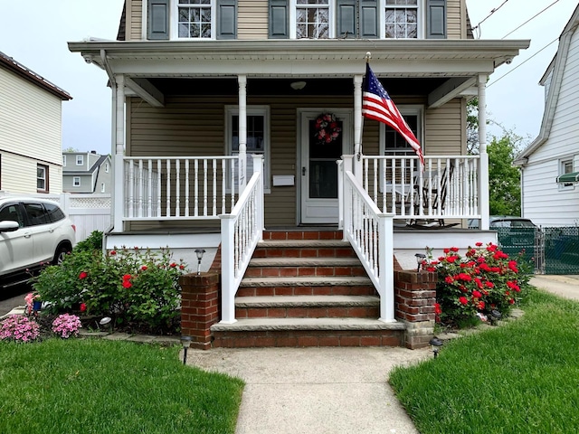 doorway to property with a porch and fence