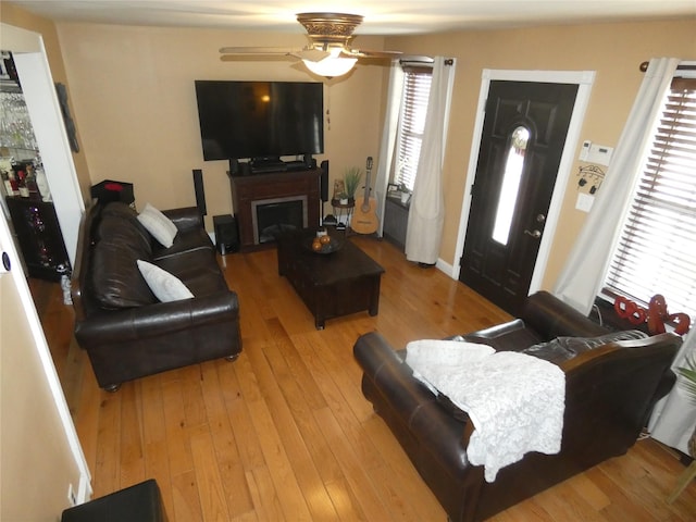 living room featuring a fireplace, light wood-style floors, and a ceiling fan