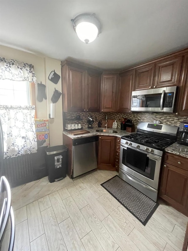 kitchen featuring light wood-type flooring, appliances with stainless steel finishes, a sink, and backsplash