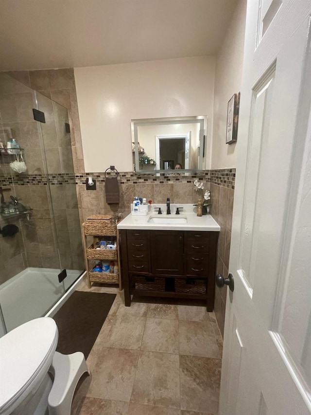 full bath with a shower stall, vanity, tile walls, and toilet