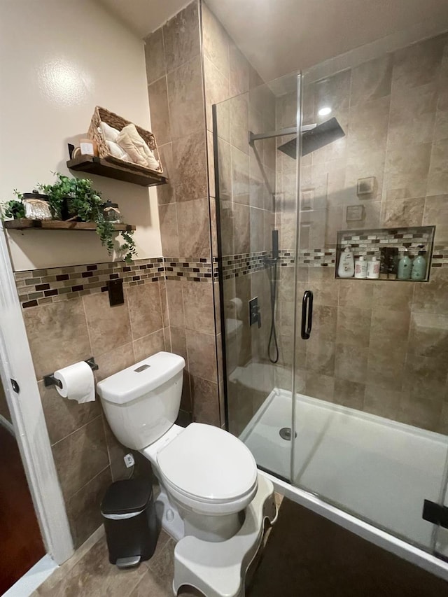 full bathroom featuring tile patterned flooring, toilet, wainscoting, tile walls, and a stall shower