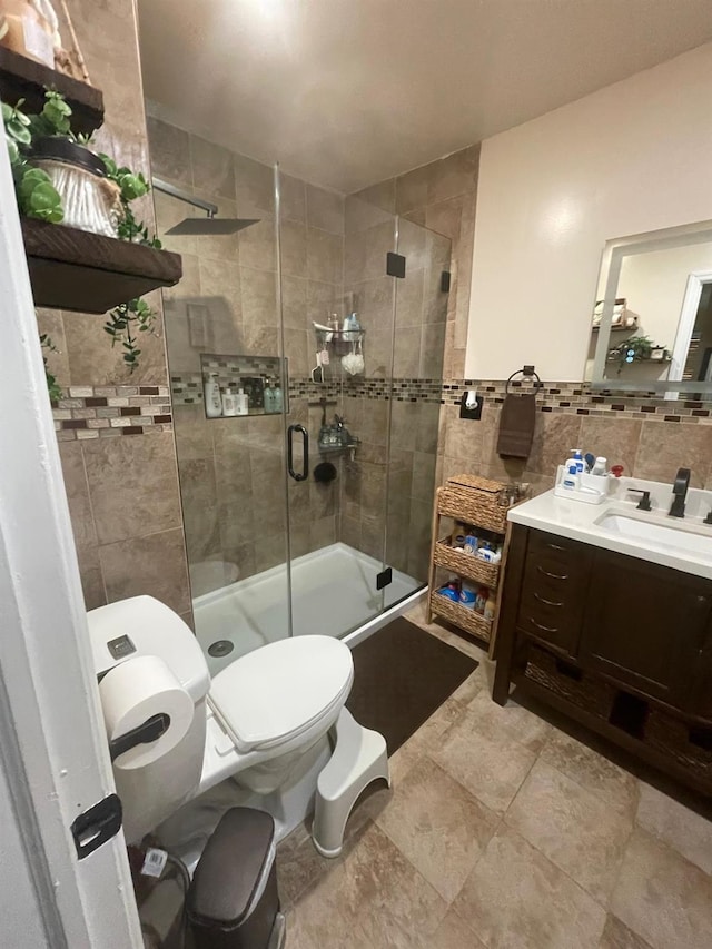 full bath with vanity, a stall shower, toilet, decorative backsplash, and tile walls