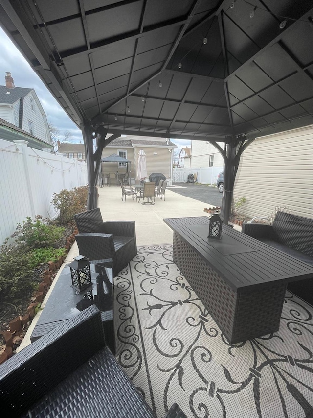 view of patio featuring outdoor lounge area, a gazebo, a fenced backyard, outdoor dining space, and an outbuilding
