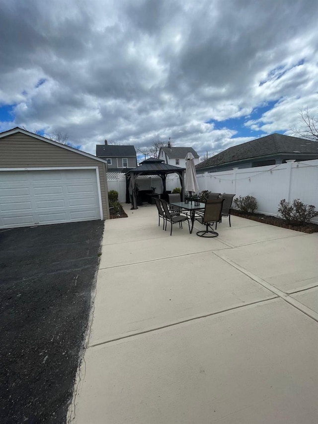 view of patio featuring outdoor dining area, a gazebo, fence, and an outdoor structure
