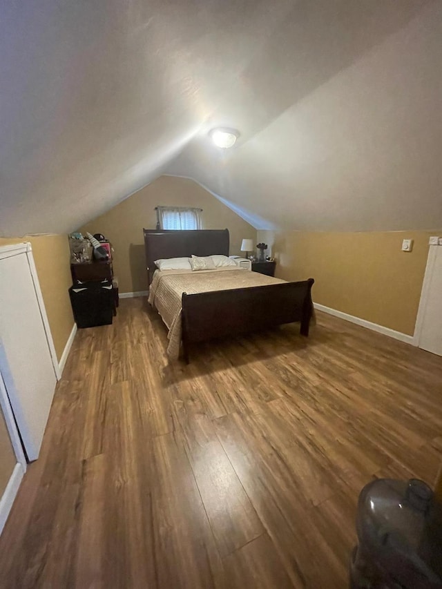 bedroom featuring baseboards, vaulted ceiling, and wood finished floors