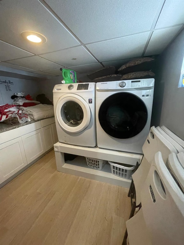 laundry room with cabinet space, washing machine and dryer, and light wood-style floors