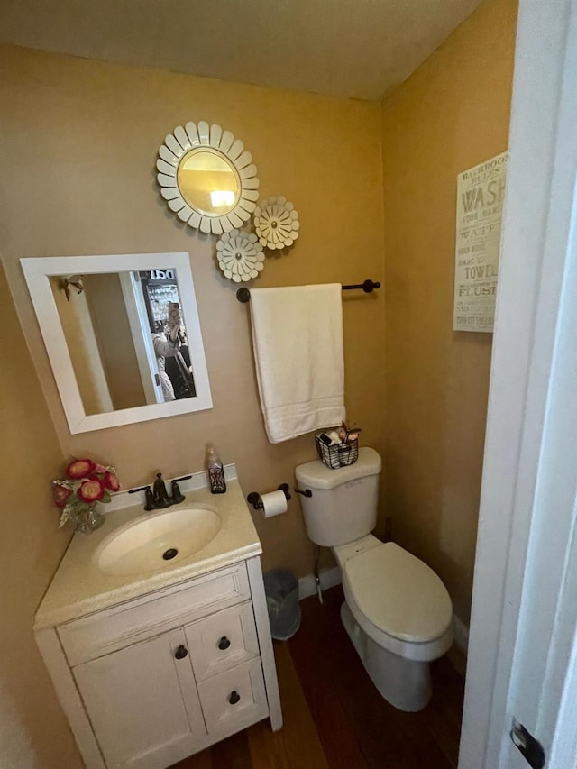 bathroom featuring toilet, vanity, and wood finished floors