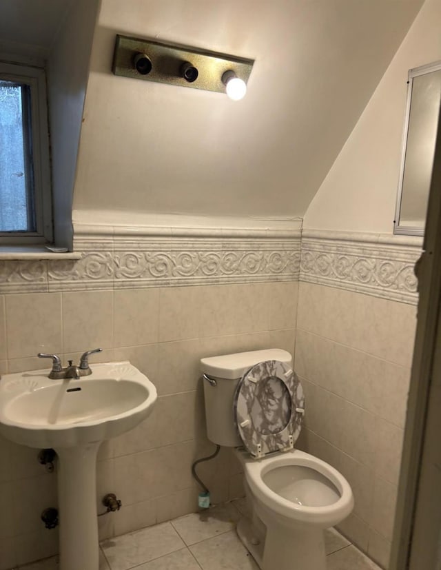 half bathroom featuring wainscoting, toilet, tile patterned flooring, and tile walls