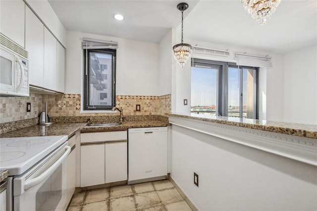kitchen featuring a chandelier, white appliances, white cabinetry, and a sink