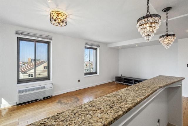 kitchen with an inviting chandelier, a wealth of natural light, a wall mounted AC, and wood finished floors
