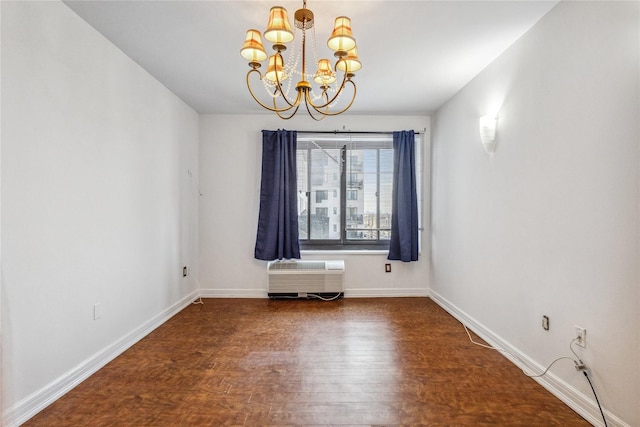 unfurnished room featuring a notable chandelier, a wall unit AC, wood finished floors, and baseboards