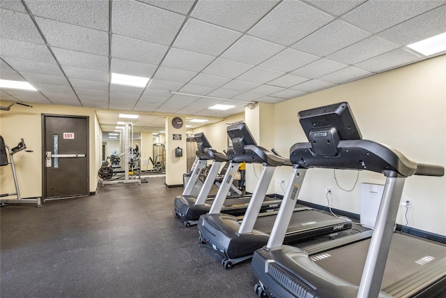 exercise room featuring baseboards and a drop ceiling