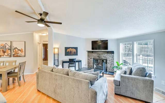 living room featuring visible vents, baseboards, ceiling fan, light wood-type flooring, and a fireplace
