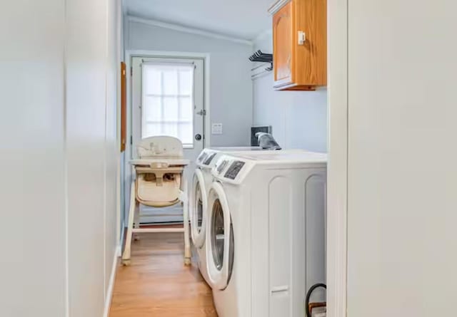 washroom featuring separate washer and dryer, a sink, ornamental molding, light wood-type flooring, and cabinet space