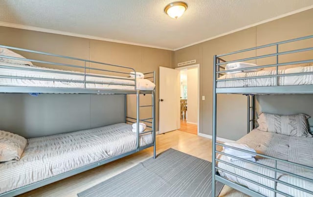 bedroom with a textured ceiling, wood finished floors, and ornamental molding