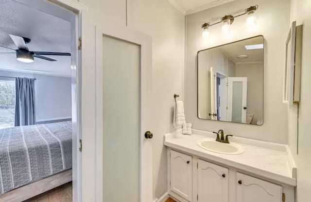 bathroom with crown molding, ceiling fan, and vanity