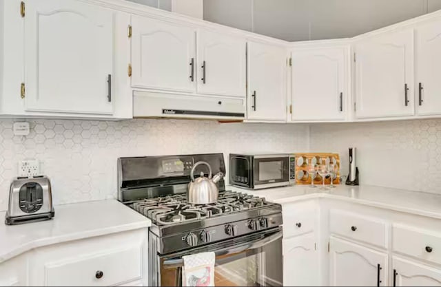 kitchen with under cabinet range hood, light countertops, black gas range, and white cabinets